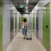 Woman pulling luggage through a secure self-storage facility hallway.